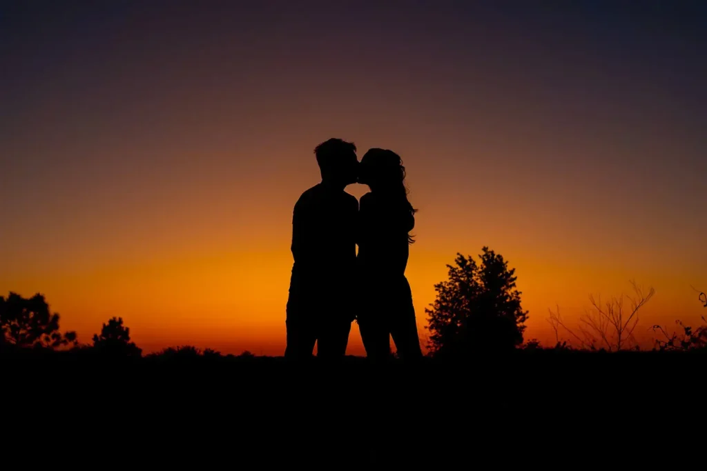 couple kisses in the orange glow of sunset