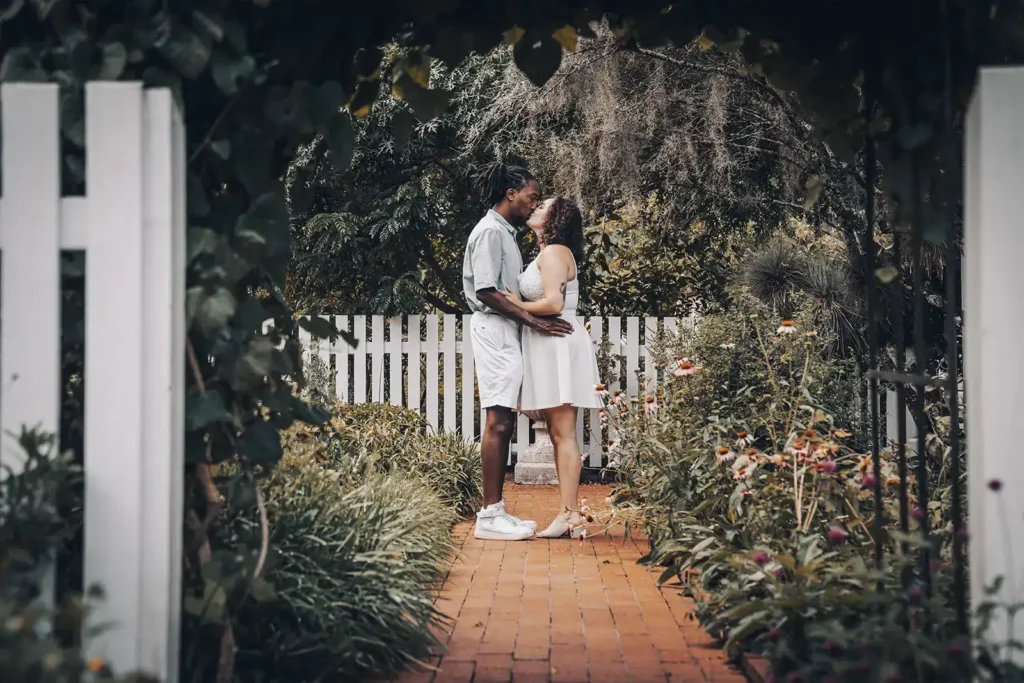couple kisses in a garden for an engagement shoot