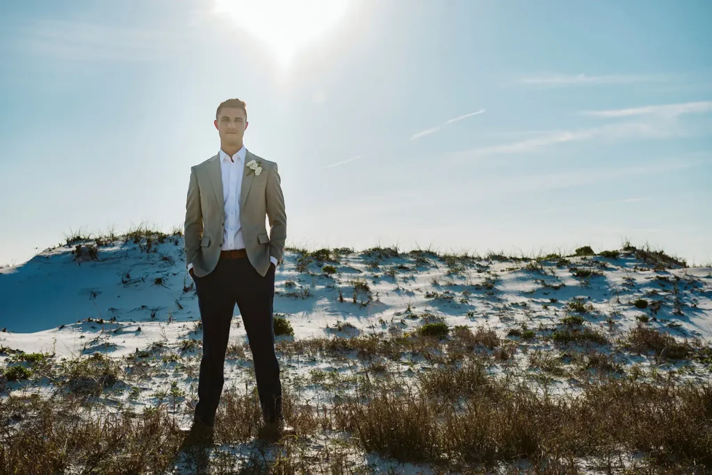 Groom standing on sand dune on wedding day