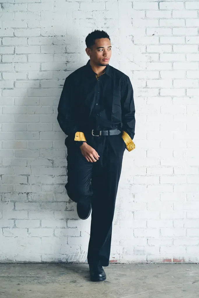 Young man leaning on white brick wall