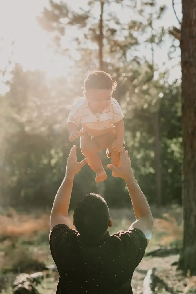 Father tosses toddler son in the air during family portrait session by Cona Studios, FL