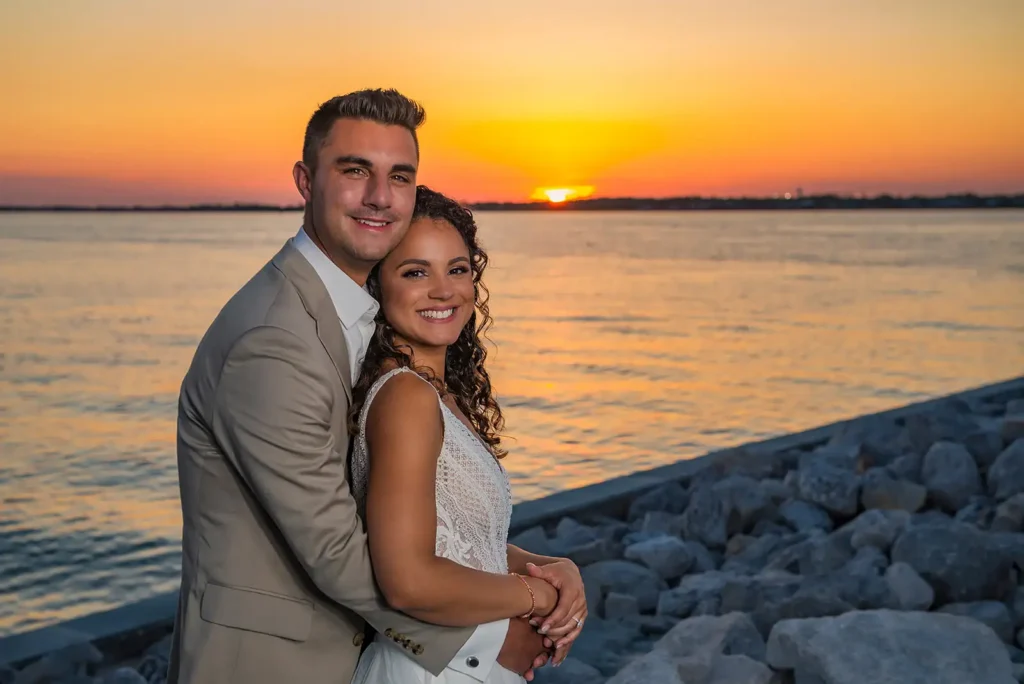 Bride and groom by the water and sunset