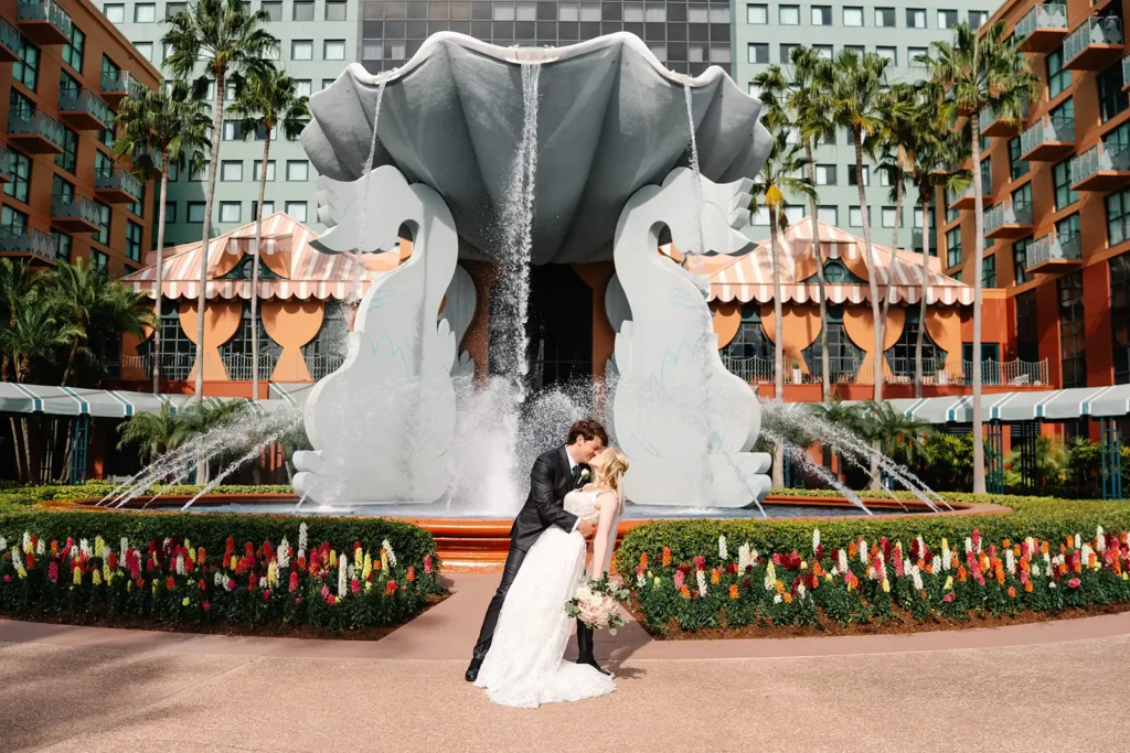 Groom dipping bride by Dolphin Resort Fountains Disney World