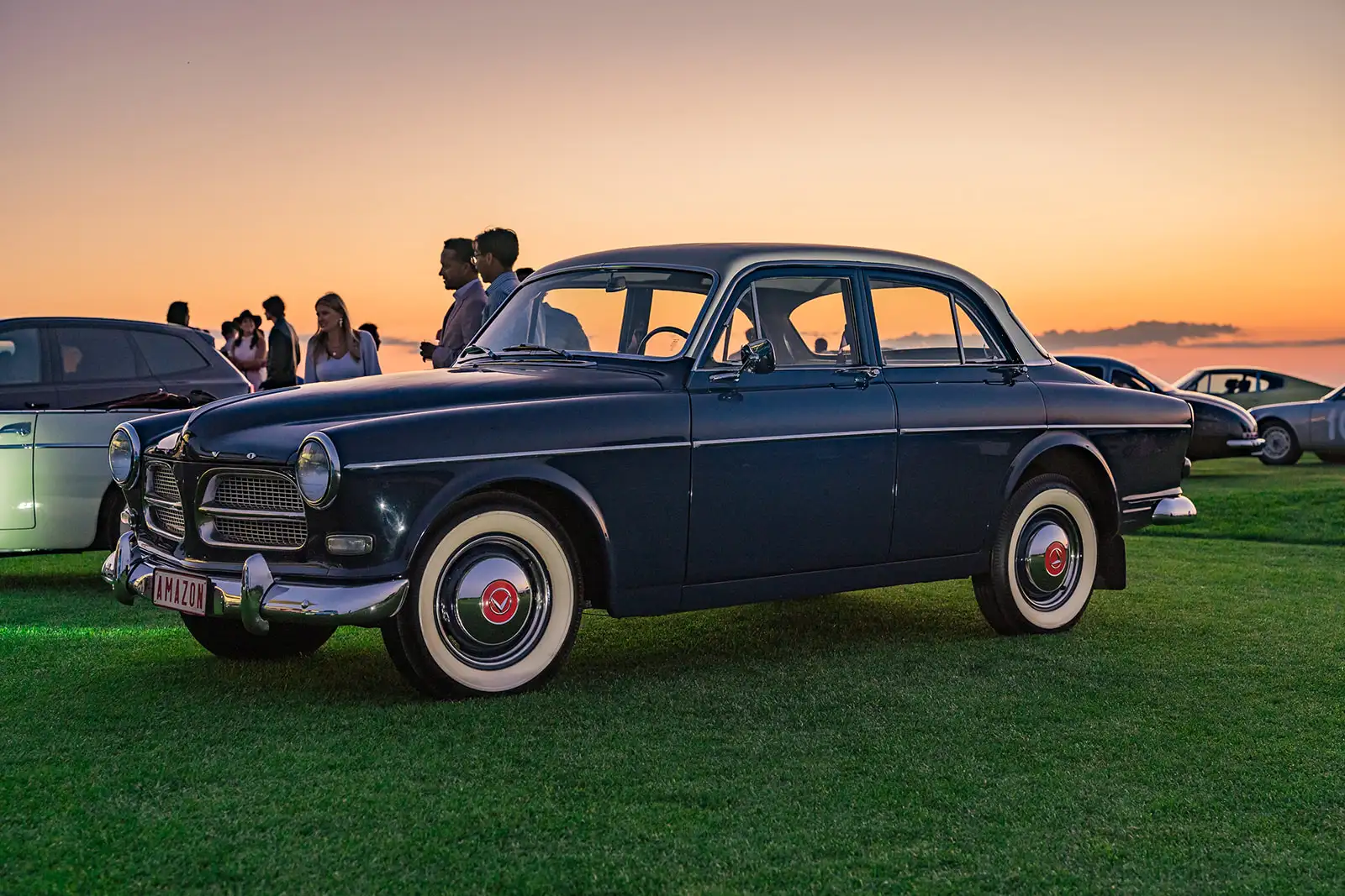 Vintage car with white walls on display at The Bridge event at sunset