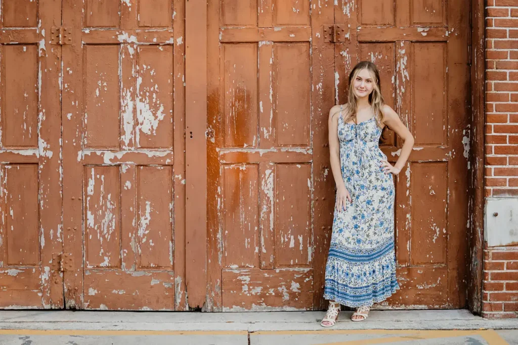 Girl by peeling red doors for senior photo in Winter Garden, FL