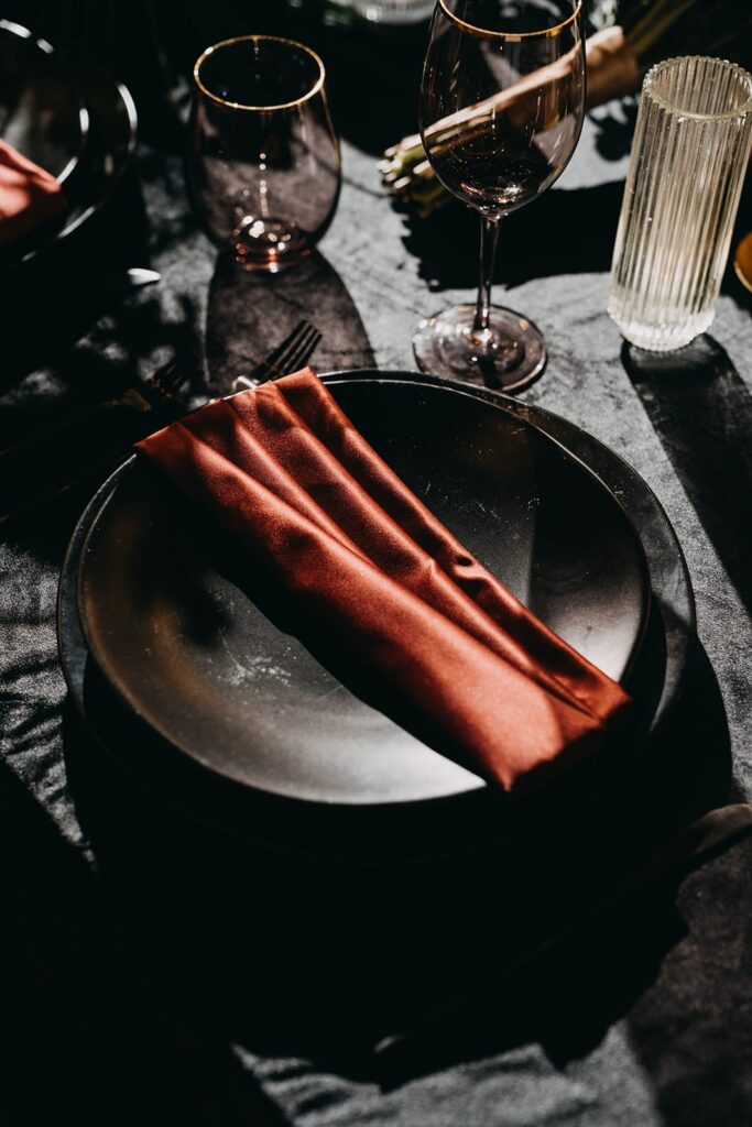 Black plates with rust napkin as wedding reception place settgin