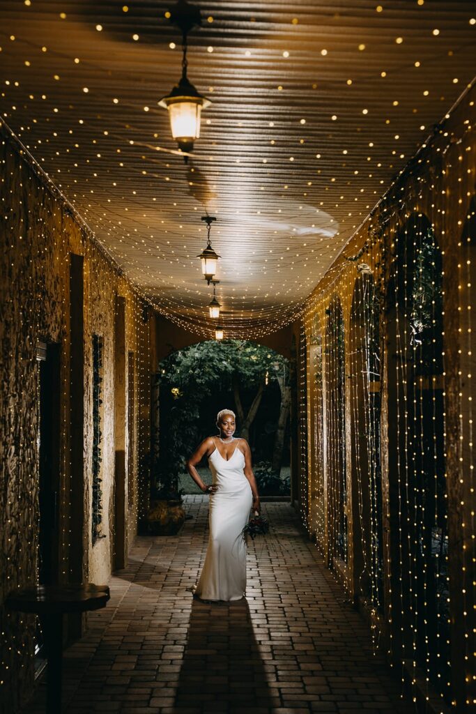 Bride standing at the end of a long canopy of twinkling lights