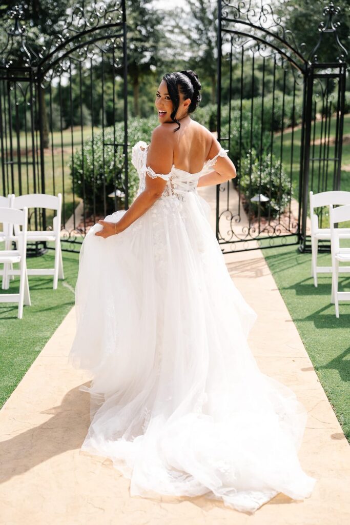 Bride looks over shoulder while running down aisle at outdoor ceremony
